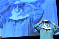  Barbara Smith, a registered nurse with Mount Sinai Health Systems, demonstrates the proper technique for donning protective gear during an Ebola educational session for health care workers in New York City.  
