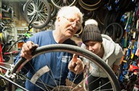  Jerry Kraynick, left, helps customer Abby Perrott, 23, of Friendship, with her bike wheel at Kraynick's Bike Shop along Penn Avenue in Garfield Tuesday. Mr. Kraynick not only provides three floors of miscellaneous bike parts for sale, but also helps teach people how to repair and care for their bikes and has spaces for customers to work on their bikes as well.