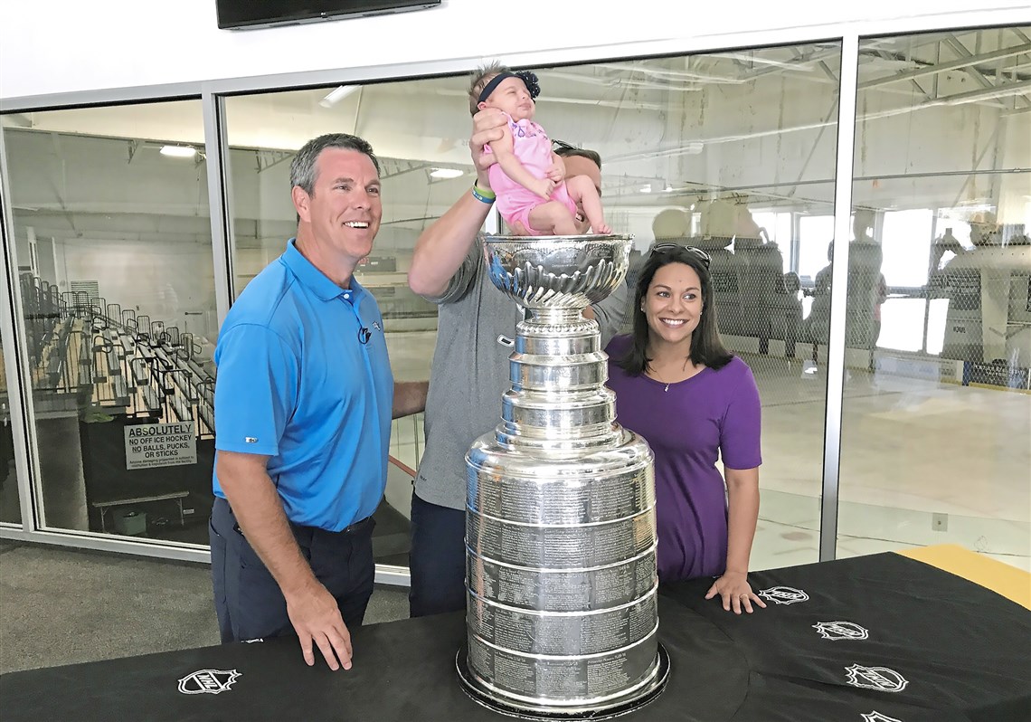 Paul and Jen Reissfelder of Plymouth, Mass., hoist their 12-day-old daughter, Evie, into the Stanley Cup as Penguins coach Mike Sullivan looks on Thursday at The Bog Ice Arena in Kingston, Mass.