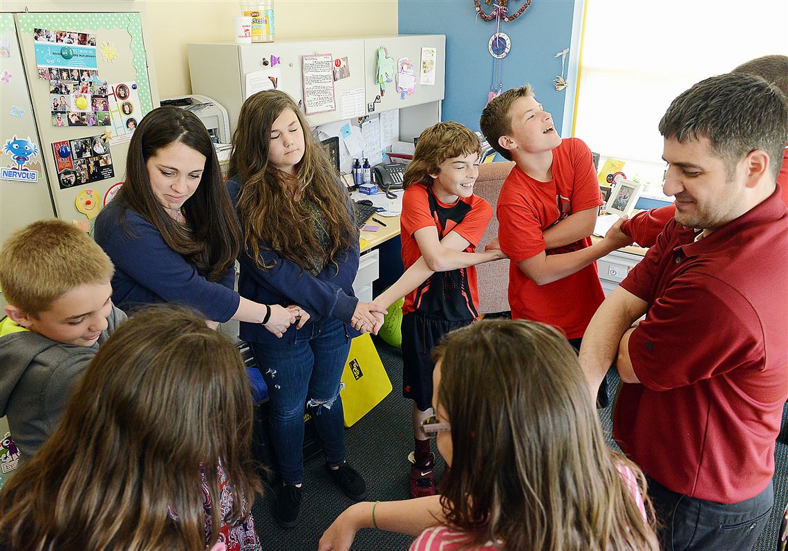 The grief support group links arms to wish for good thoughts at the end of their session at Ross Elementary School. Shawn Sledzianowski, a child grief specialist at Highmark's Caring Place, is at right. School counselor Dawn McElhinney is at left.