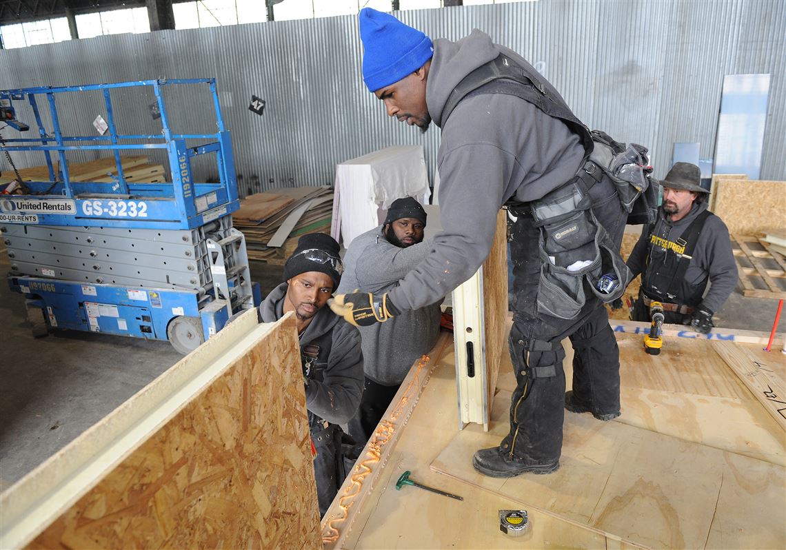 From left, Donta Bell, Darrick Curington and Lee Brown of Homestead and carpenter Lou Mazzagetti work together on a modular home Friday at Work Pittsburgh’s site in the South Side.