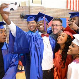 Seniors pose for a photograph with Jason Boll, an English teacher, before commencement at Wilkinsburg High School in June. 